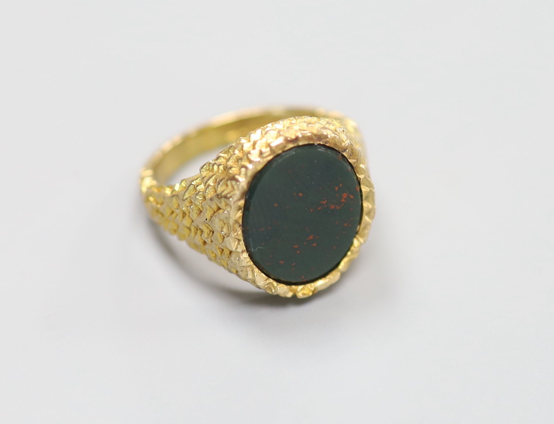 A modern 9ct gold and bloodstone set oval signet ring, with textured setting, size Q